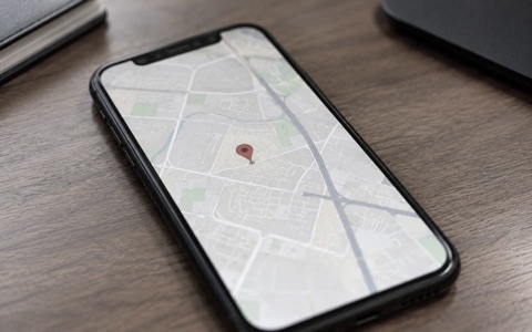 A phone on a desk showing a pin dropped on a map